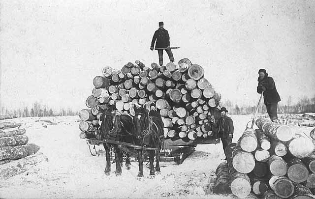 Crew with loaded sled of logs.