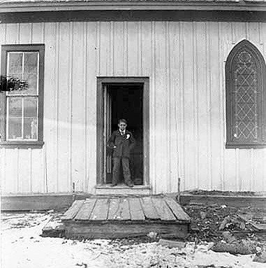oung boy standing in doorway of a church at an Indian boarding school, location unknown, ca. 1900.