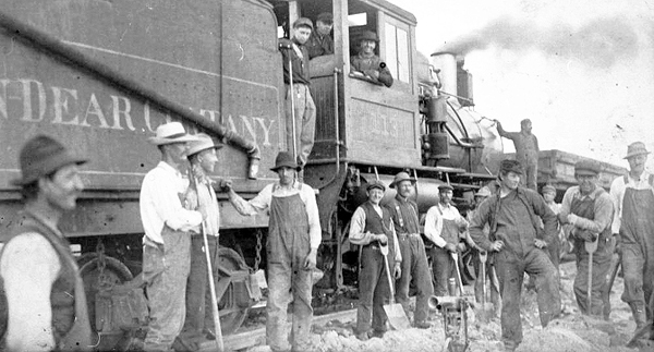 Mining laborers beside Winston-Dear Company train, engine #113, Hibbing, Minnesota, 1900 - 1914.