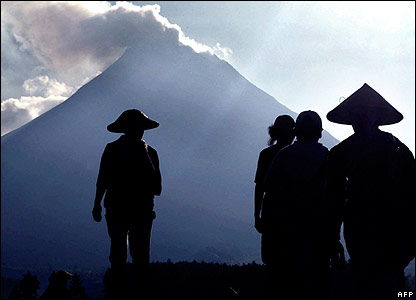 Java farmers silhouetted against volcanic Mount Merapi.