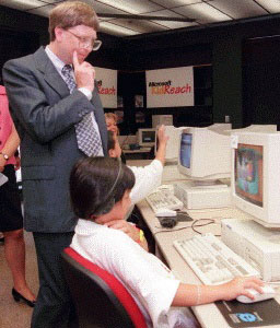 Bill Gates watching youth at computer.
