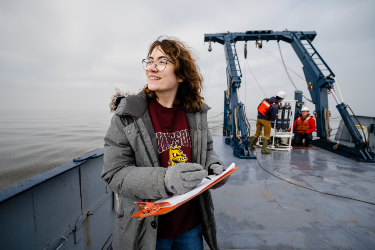Student researcher recording data on the deck of the Blue Heron.