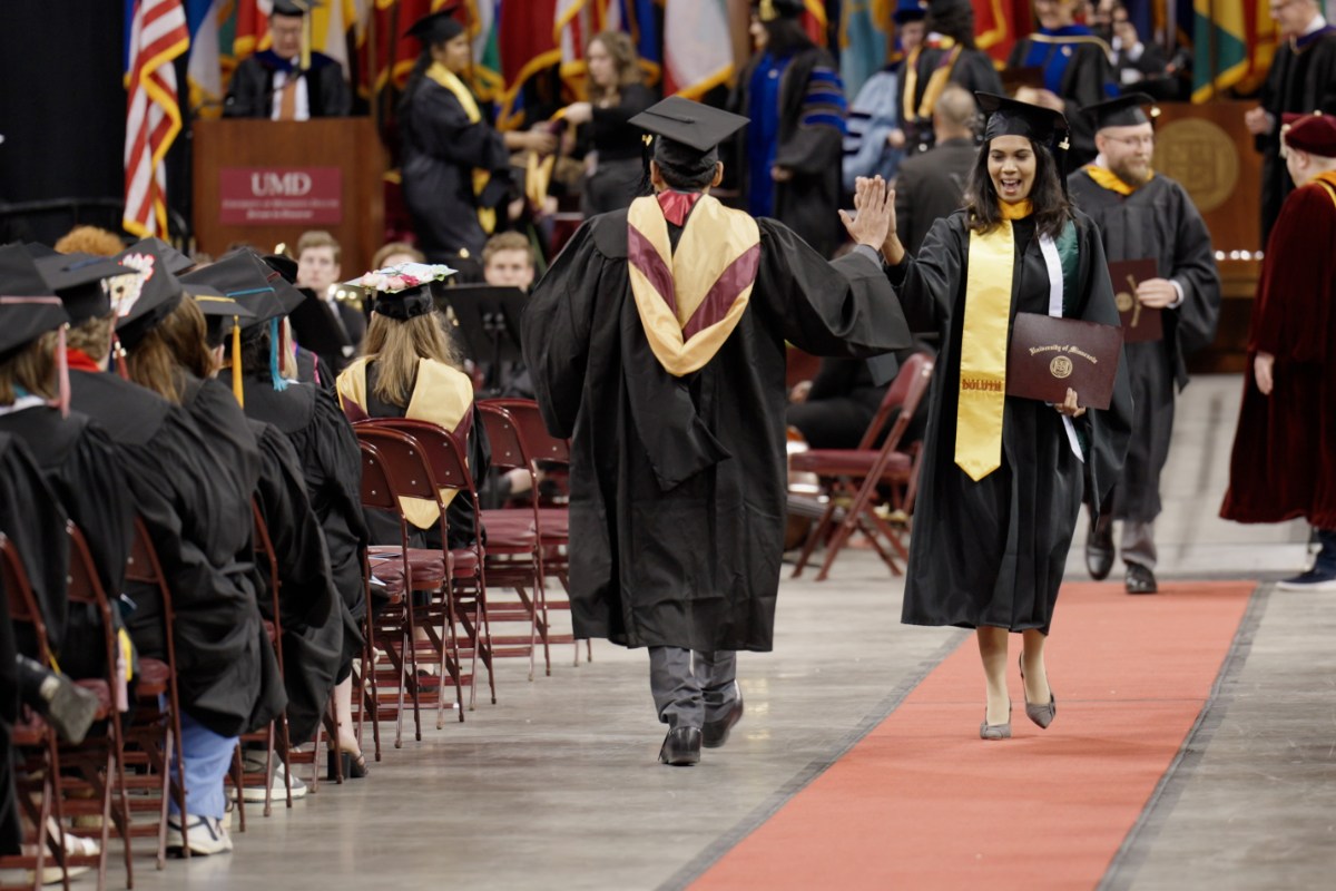Grads high-five each other during 2023 Commencement ceremony.