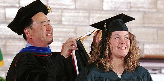 Faculty member hoods a graduate student during commencement.