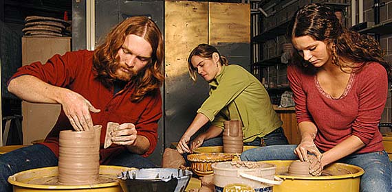 Two art students and a professor mold clay vases on the new pottery wheels in the UMD ceramics studio.