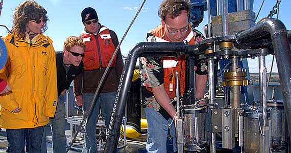 Geological Sciences professors Doug Ricketts (right), Christina Gallup (left) and students remove a sediment core from the bottom of Lake Superior on the research vessel the Blue Heron.