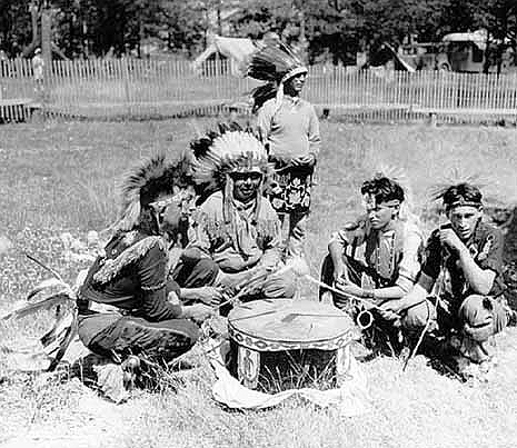 Indian drummers from Cass Lake beating drum during celebration commemorating peace treaty between Chippewas and Sioux, 75th anniversary, 1938.