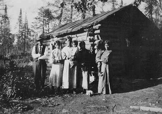 Indian family in front of log home., ca. 1915.