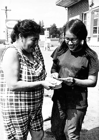 Mother and daughter dividing the day's wild rice harvest proceeds, 1970