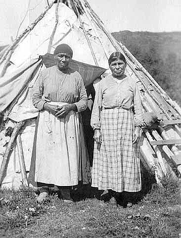 Mrs. Tamarack and Mrs. Mary Spruce, wives of Joe Spruce, in front of wiigwaam near Grand Portage, 1922.
