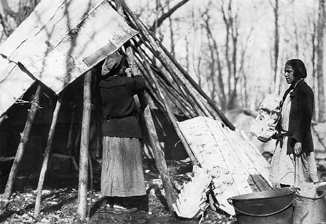 Mrs. John Door and Anna Davis Door Building a birch bark tepee at maple sugar camp, Mille Lacs Reservation, ca. 1925