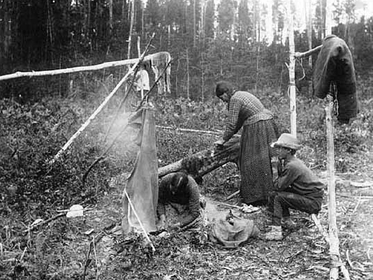 Chippewa Indians smoking and scraping buck skins, 1900.