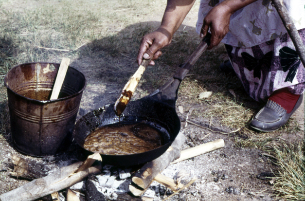 Cooking balsam pitch mixed with ashes for use in building a canoe, Mille Lacs, 1959