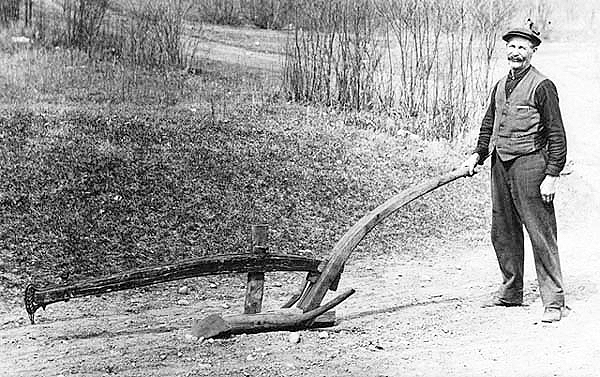 Man displaying an old Scandinavian plow, ca. 1910.