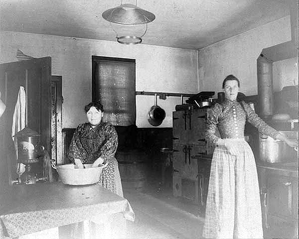 Two women in kitchen at Indian boarding school, location unknown, ca. 1900.