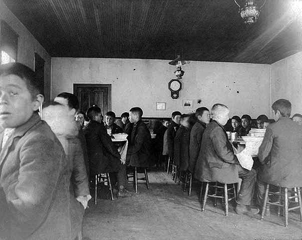 Young boys eating in the dining hall, Indian boarding school, location unknown, ca. 1900.