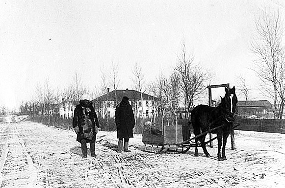 Two men and horse drawn sled at an Indian boarding school, location unknown, ca. 1900.