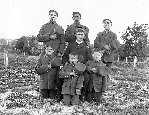 Teacher and young boys posed for photograph, Indian boarding school, location unknown, ca. 1900.