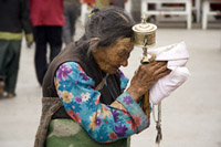 An elderly Tibetan women holding a prayer wheel on the Lhasa's pilgrimage circuit of Barkhor. The Barkhor, a quadrangle of streets that surrounds the Jokhang Temple, is both the spiritual heart of the holy city and the main commercial district for Tibetans.