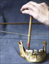 "Researchers using a bow and flint-tipped drill to bore through a tooth."