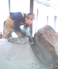 Pat applying second coat of plaster to outside of oven.