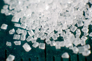 Macro photograph of a pile of sugar (saccharose).  The sugar was on a ruler, and the black marks are 1mm apart.