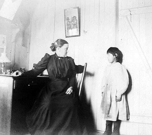 Teacher and student (?) at an Indian boarding school, location unknown, ca. 1900.