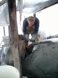 Pat applying scratch coat of plaster on outside of oven.